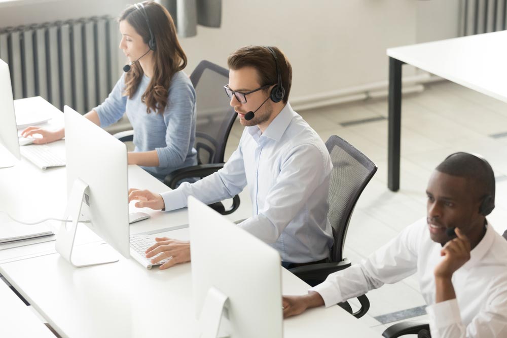Diverse call center operators team use computers consulting clients in office